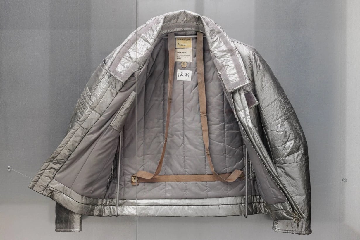 Helmut Lang Astro Biker Jacket from 1998 shown open, featuring metallic silver fabric, quilted interior, and harness style straps, part of the MAK Helmut Lang Archive