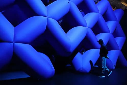 Visitor walking past a large blue inflatable tunnel installation at the Balloon Museum.