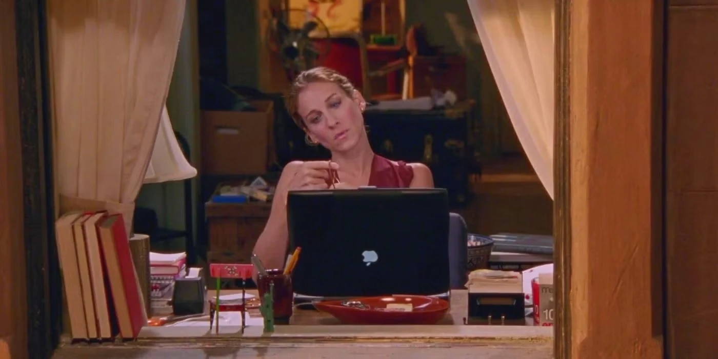 Woman writing on a laptop at a desk, focused on the screen.