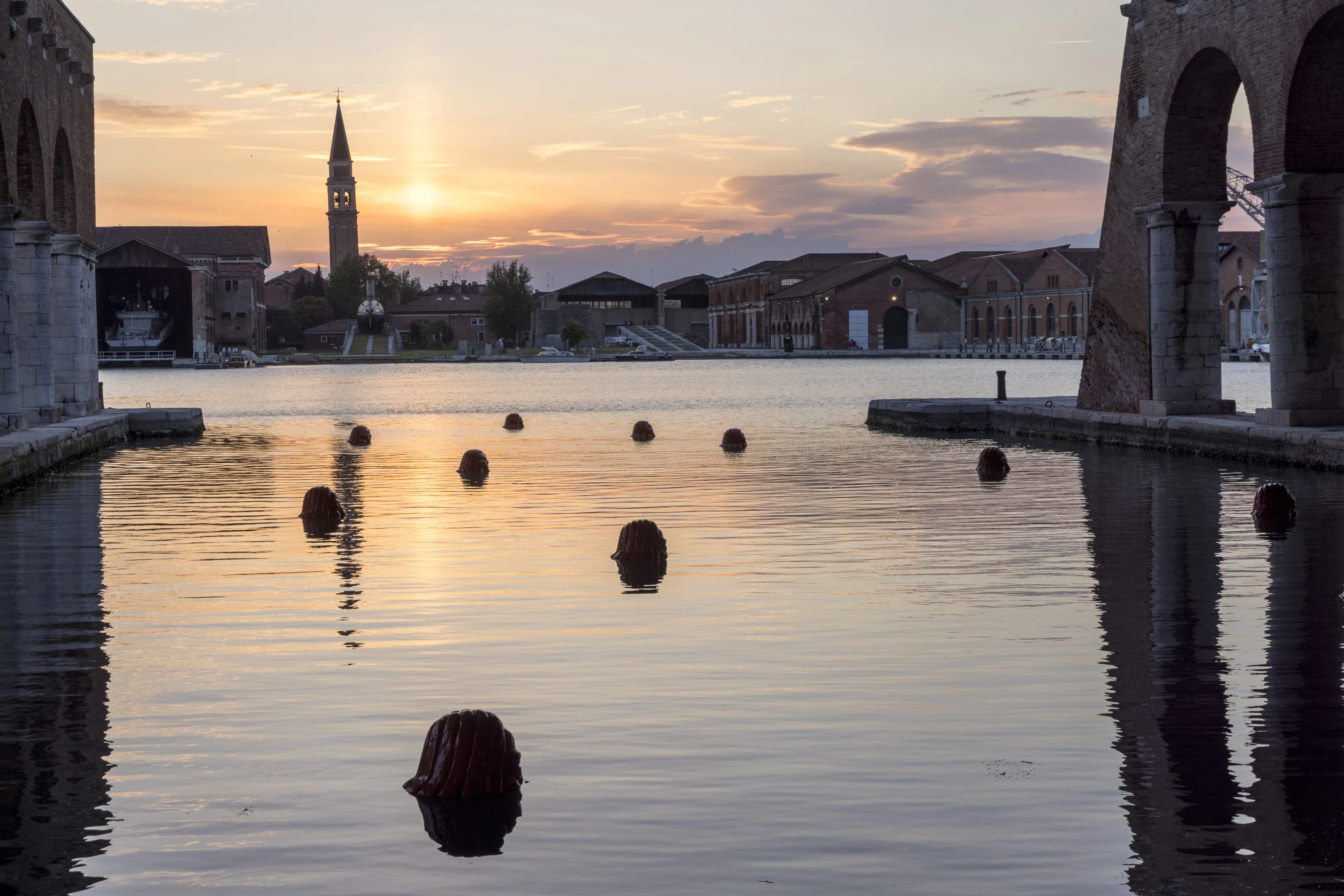 Sunset over Venice Arsenale canal with dark floating sculptures by Alice Maher, photo by Marco Zorzanello