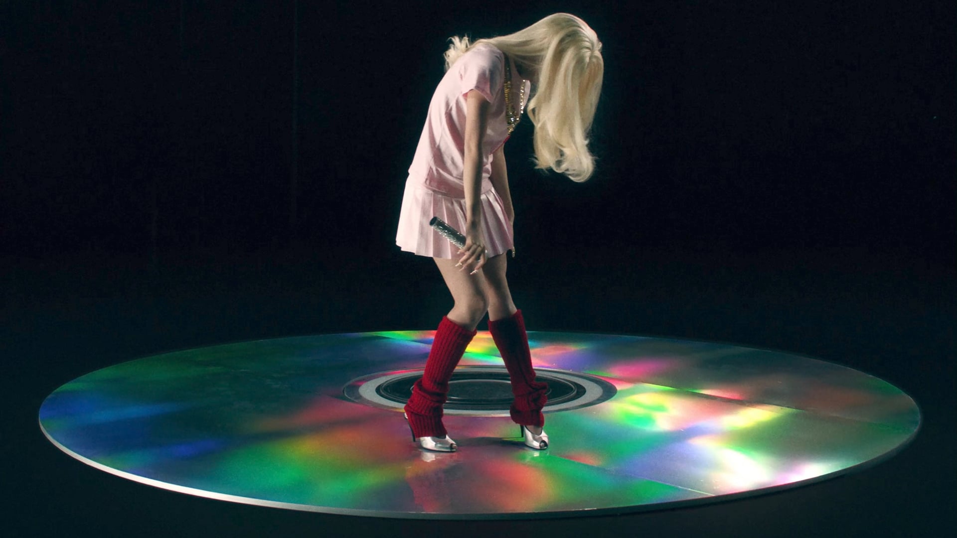 Performer on giant CD prop in pink dress and red leg warmers, Lexie Liu Pop Girl music video