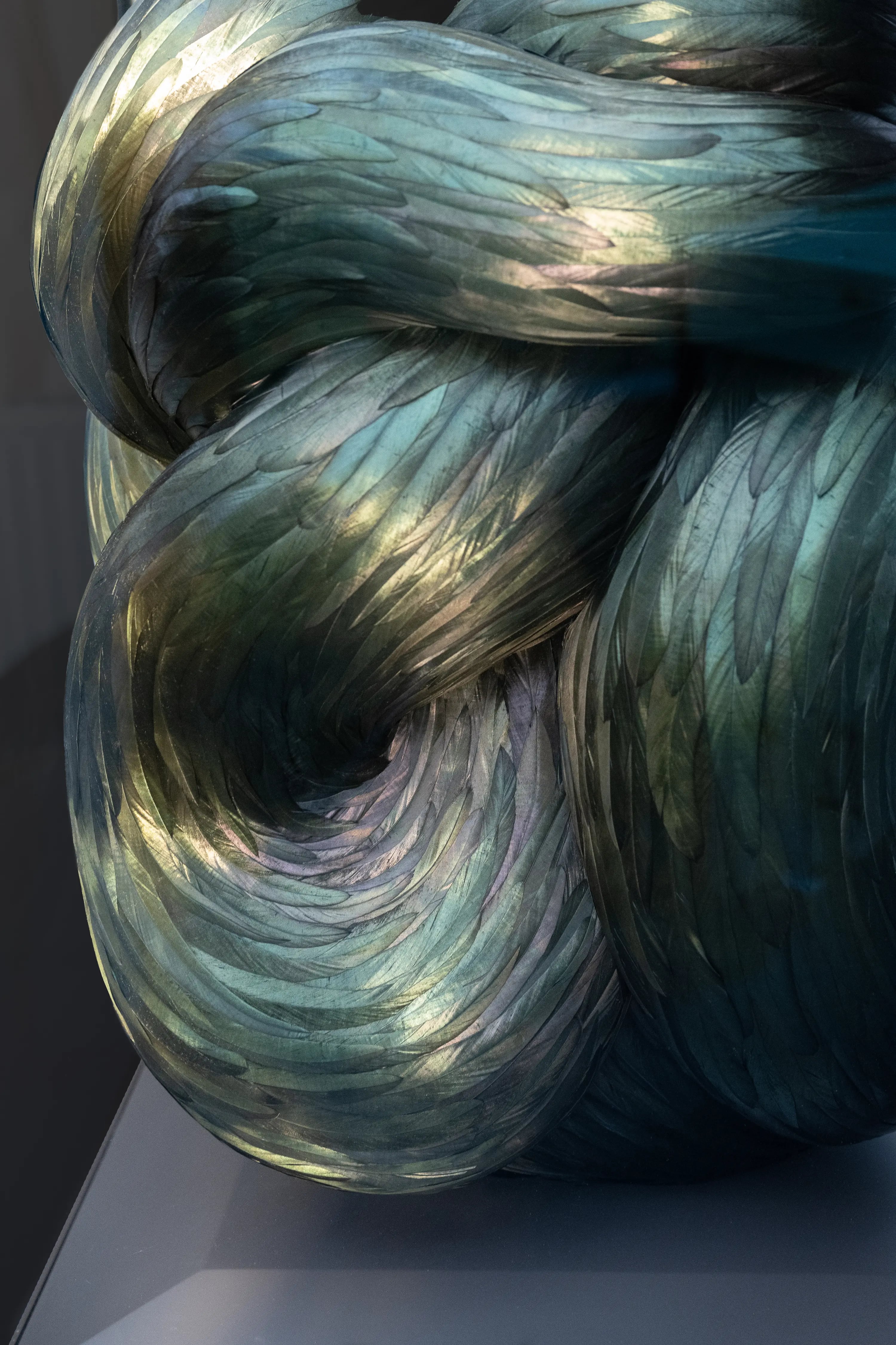 Kate MccGwire TORSION 2024 sculpture with iridescent feathers twisted into sweeping spiral forms