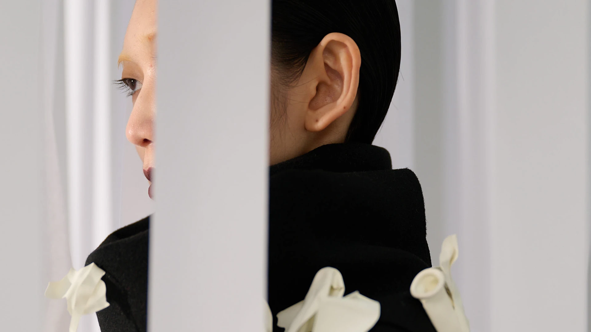 Maria Calderara S/S 25 Touch collection model in black sculptural jacket with white petal embellishments, profile view