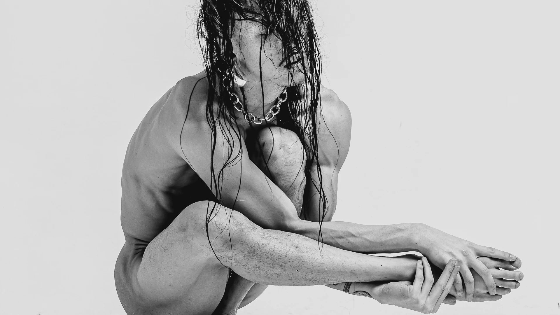 James Vu Anh Pham crouched in monochrome studio portrait, muscular figure with wet hair and chain necklace