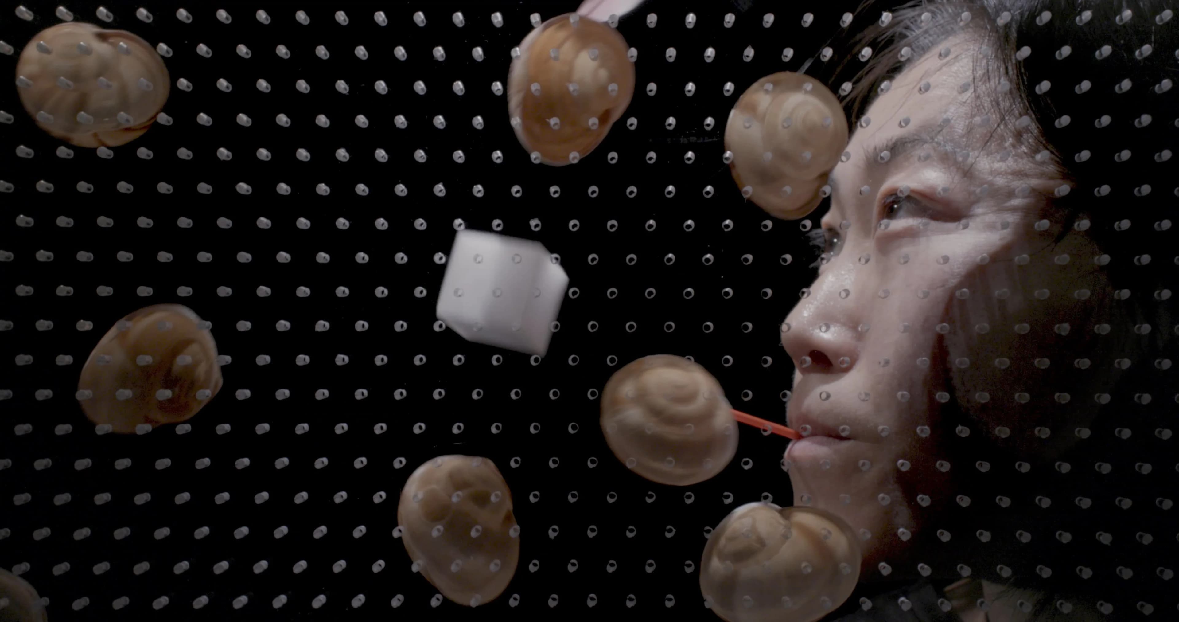 Aki Sasamoto Point Reflection: artist's face surrounded by floating snails and a cube against dark dotted background