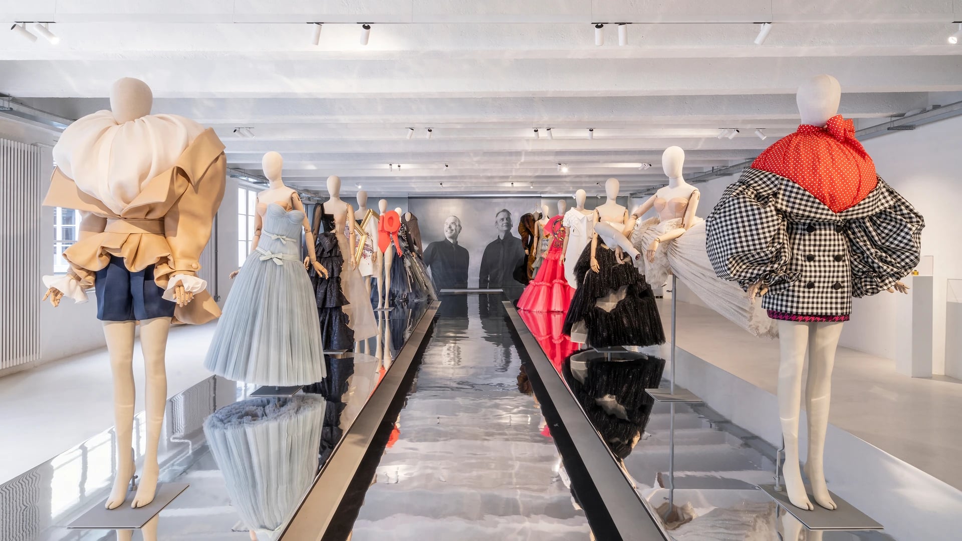 Viktor&Rolf Milan exhibition gallery with sculptural haute couture gowns on mannequins in a mirrored white space